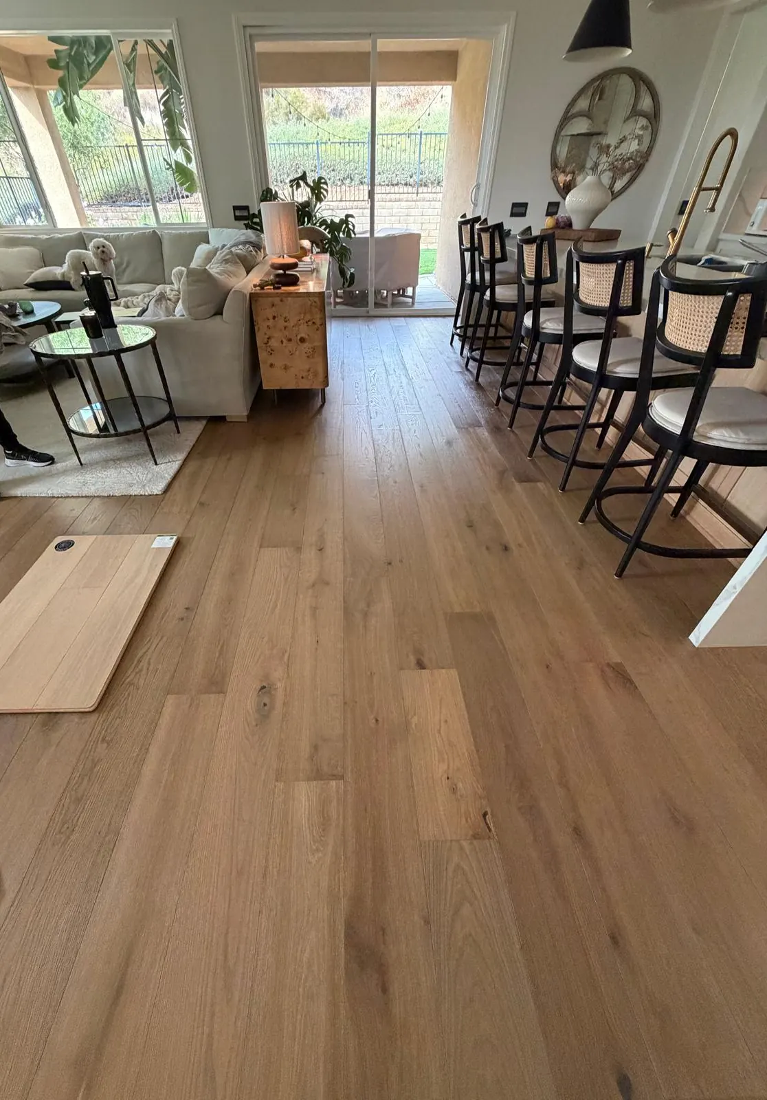 Wide plank wood-look floor installed through a bright living and dining area
