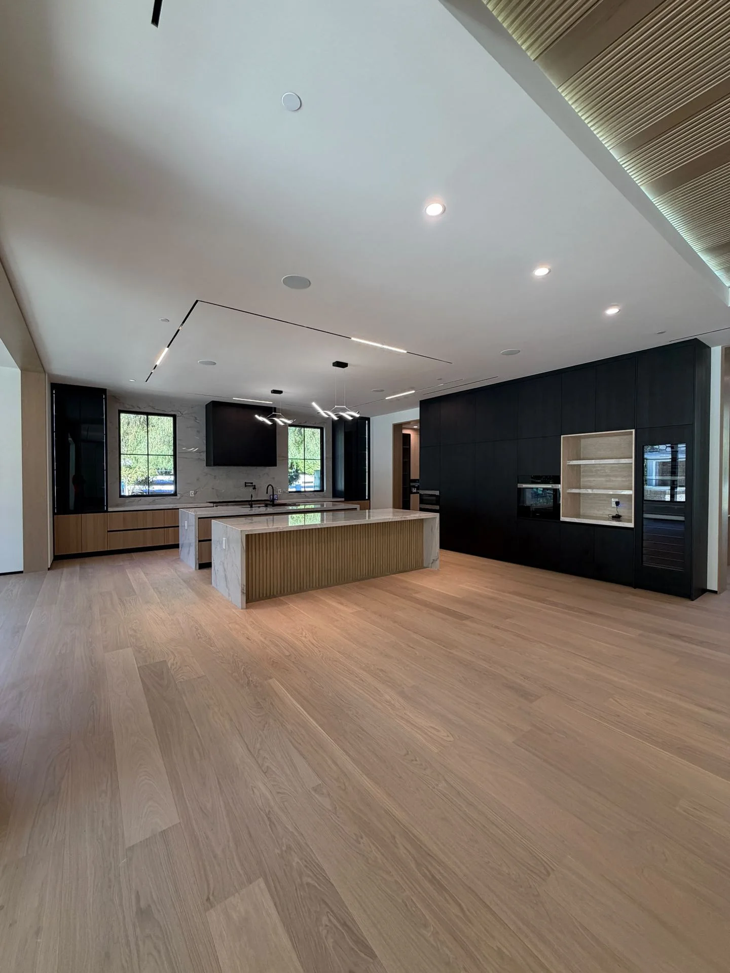 Warm wood-toned floor connecting a kitchen and living space